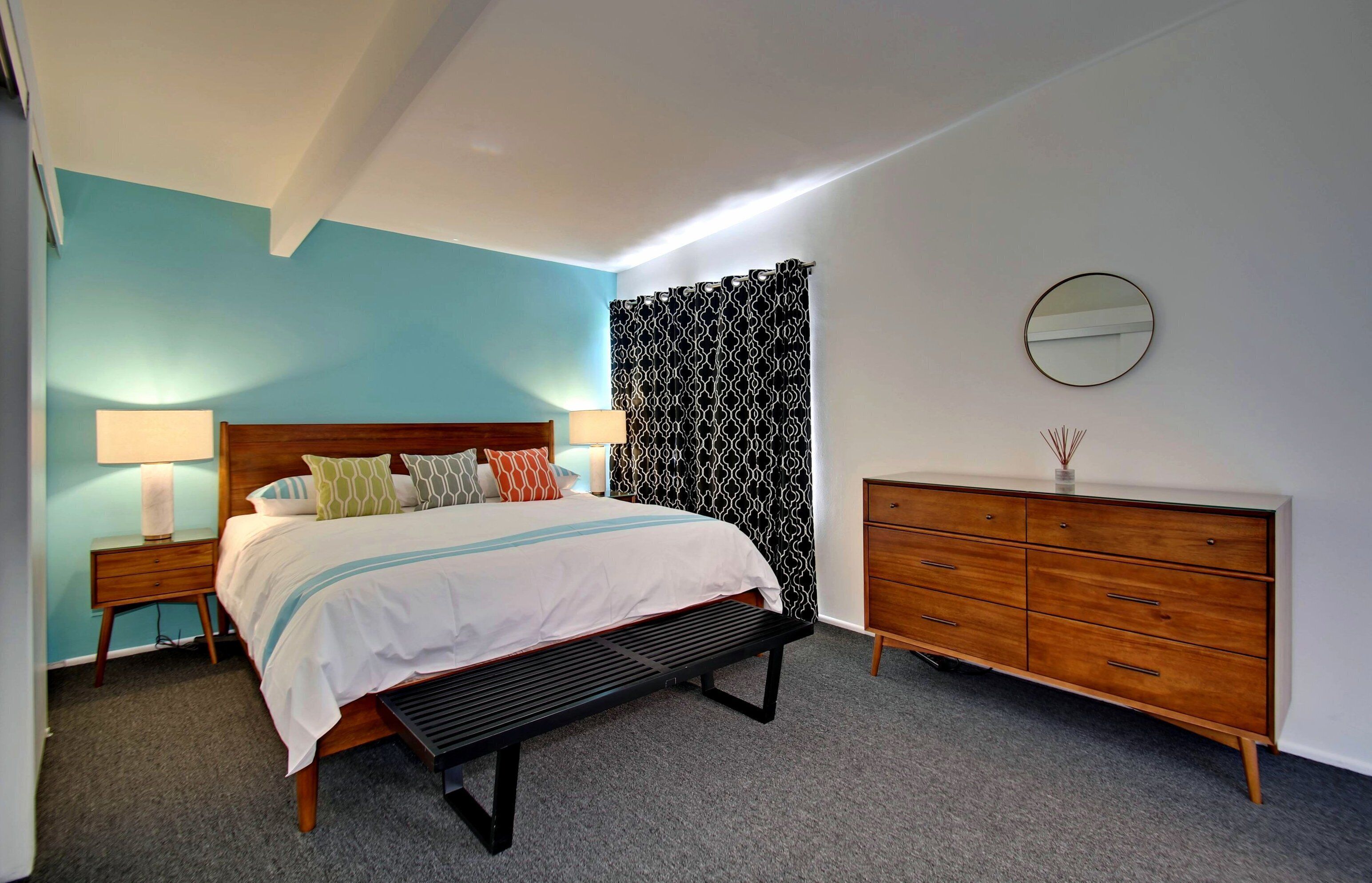 Une chambre à coucher moderne avec un lit, des tables de chevet, une commode et un miroir.