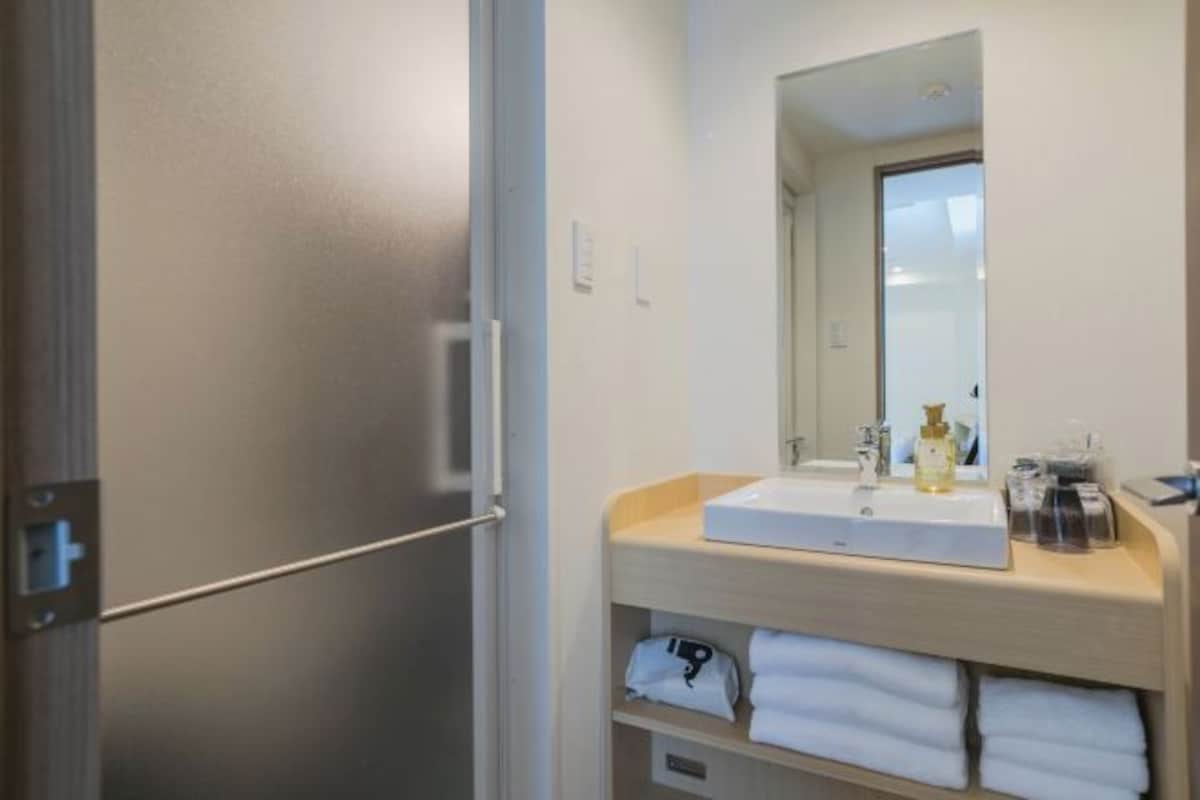 A modern bathroom with a built-in sink, mirror, and towel storage.