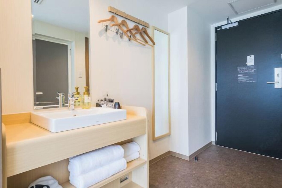 A bathroom with a white sink, mirror, and wooden towel rack.