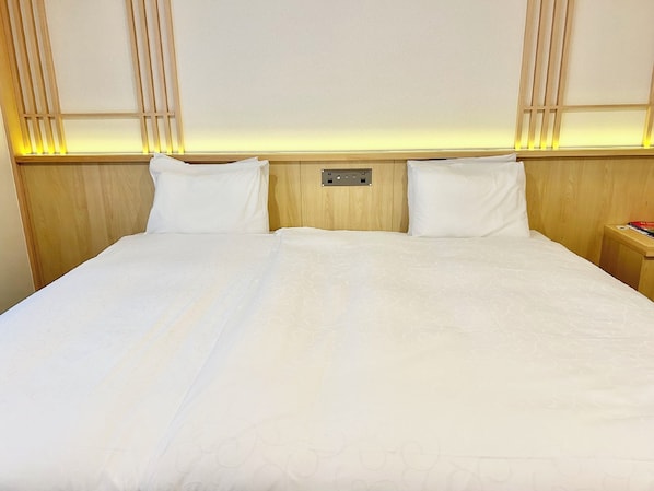 Una cama bien tendida con cabecera de madera y mesita de noche con un libro.