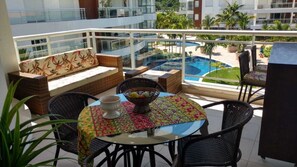 Relax in style with a sofa, chairs, and table amidst lush greenery and a serene pool view.