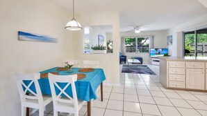 Un salon moderne comprenant un coin repas, une cuisine et un balcon offrant une vue sur l’extérieur.