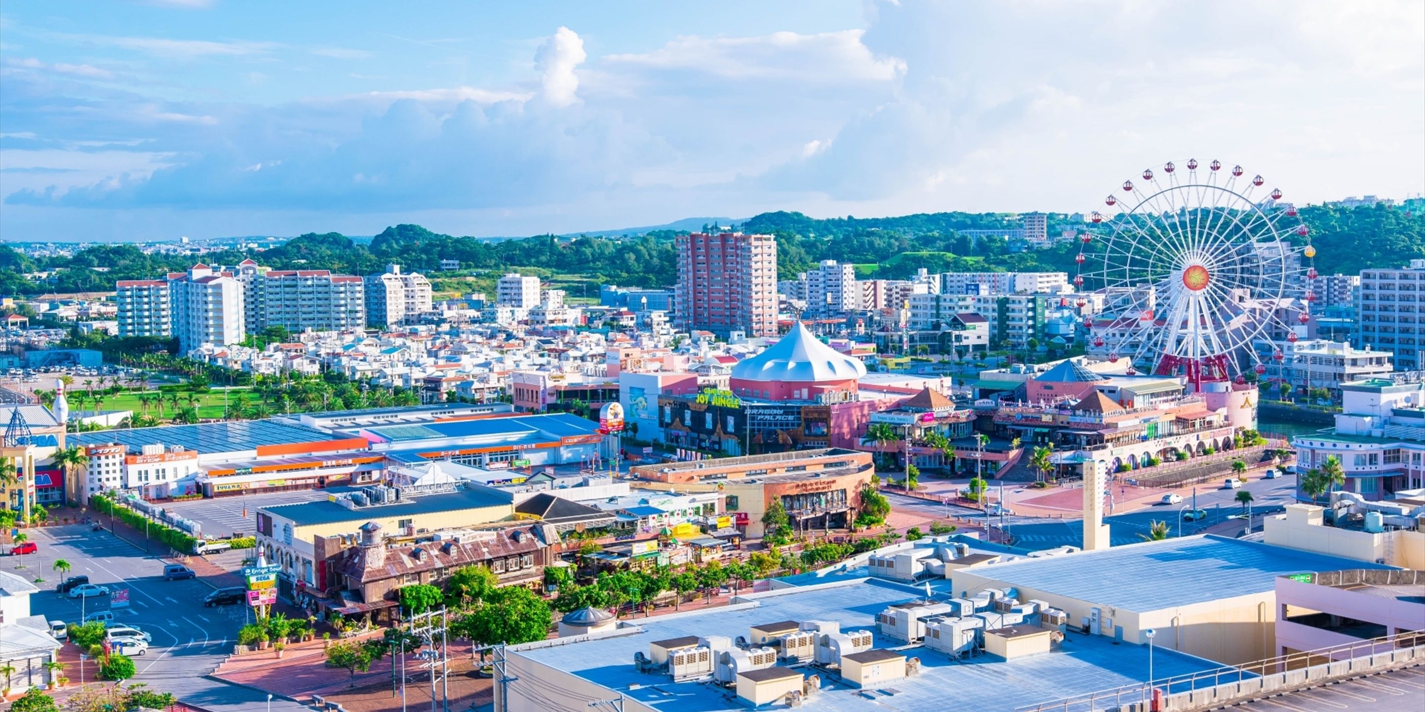 A cityscape with a prominent Ferris wheel, a large dome building, and various commercial buildings.