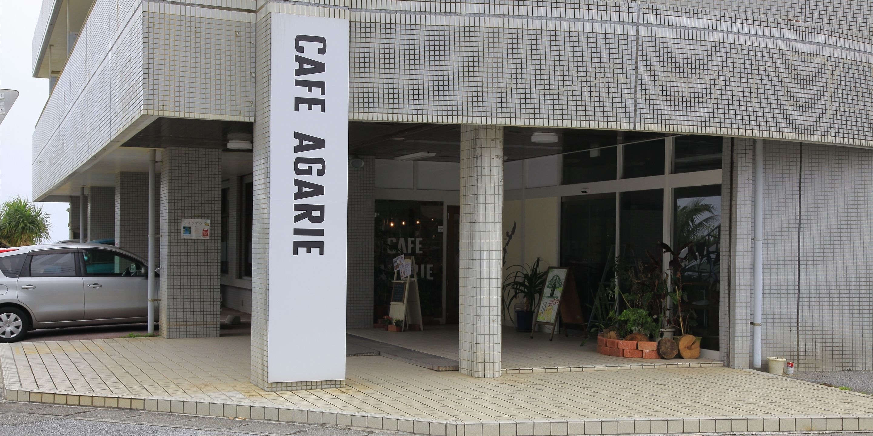 Un café à la façade recouverte de carreaux et portant une enseigne indiquant « CAFÉ AGARIE ».
