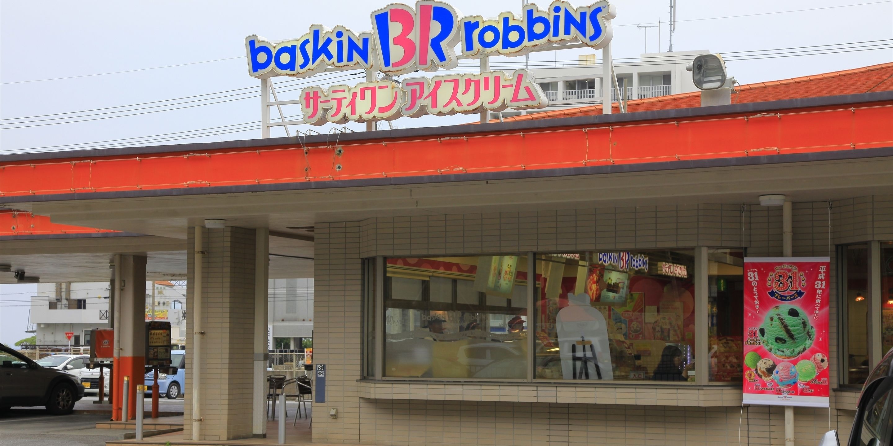 A Baskin Robbins store with a red awning and a large window display.