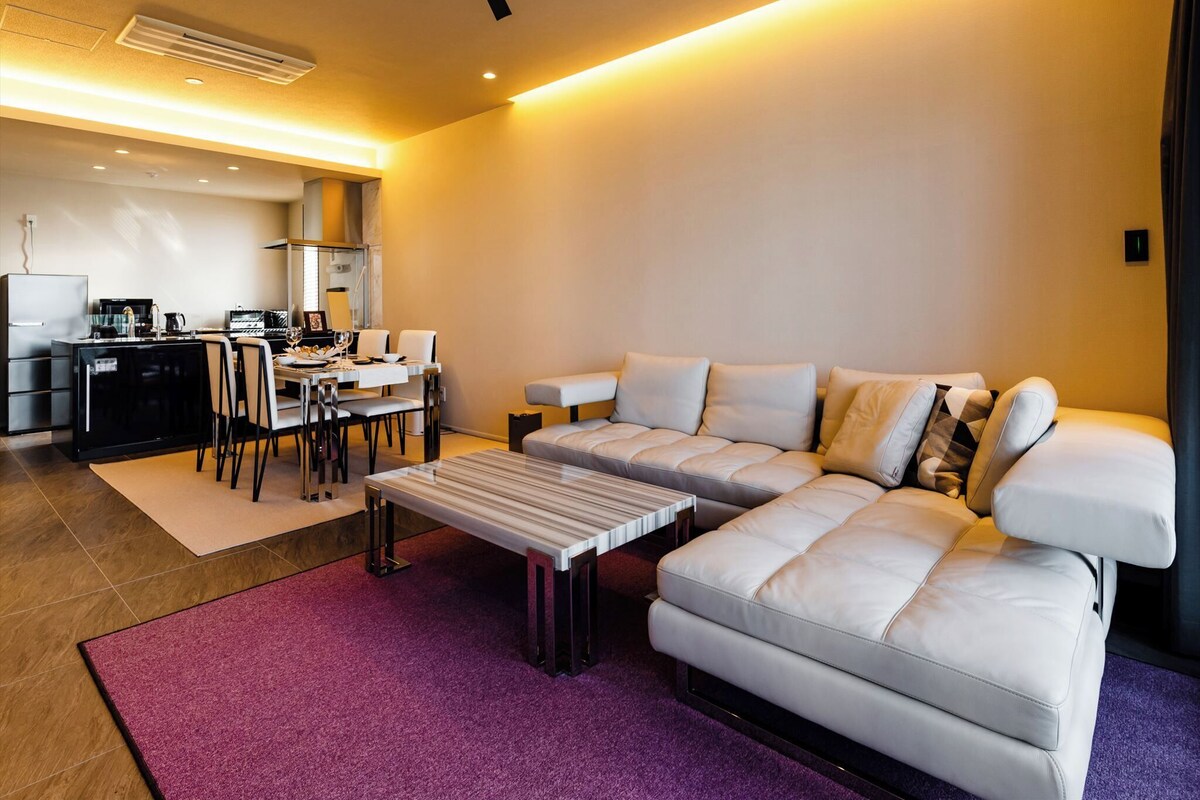 A modern living room with a sofa, coffee table, and dining area.