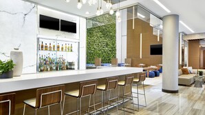 Un área de bar moderna con mostrador de mármol, taburetes y una pared vertical con jardín.