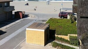 A residential area with a beach view, a parking lot, and a small building with a brick facade. - Ocean and Beach View Townhouse at Mandalay Beach in Oxnard, California (Oxnard)