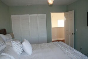 A bedroom with a bed, white pillows, a closet, and a door leading to another room. - Ocean and Beach View Townhouse at Mandalay Beach in Oxnard, California (Oxnard)