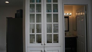 A white cabinet with glass doors containing plates and bowls. - Ocean and Beach View Townhouse at Mandalay Beach in Oxnard, California (Oxnard)