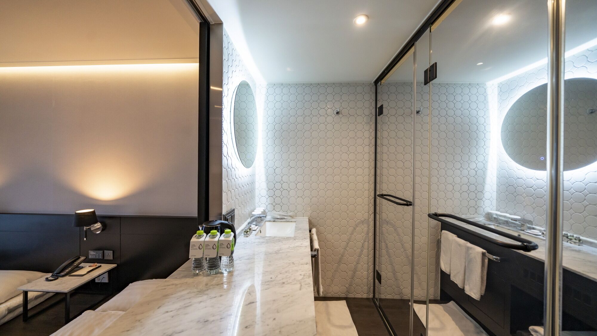 Une salle de bain moderne avec un comptoir en marbre, une douche en verre et un grand miroir.