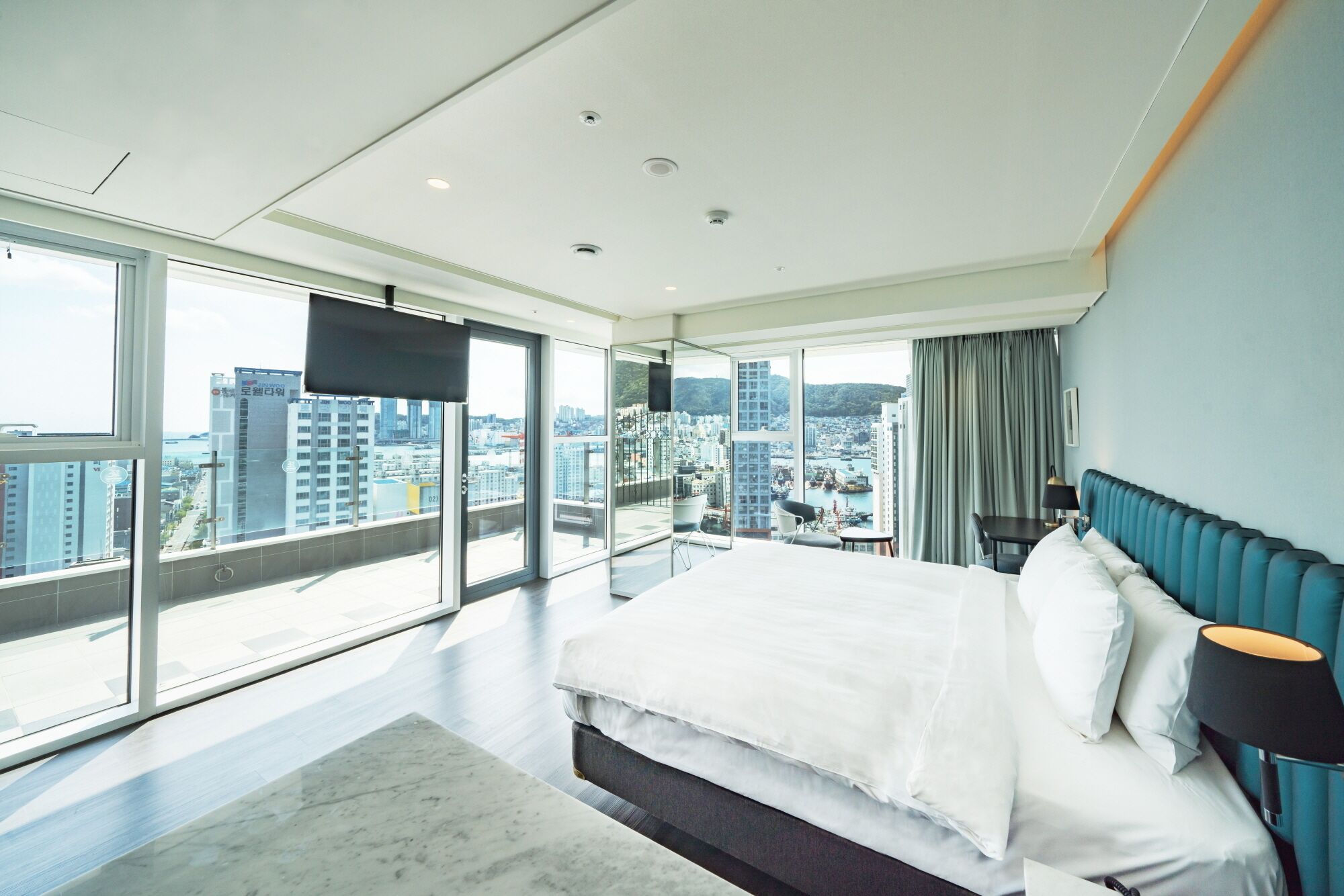 A modern hotel room with a large bed, a view of the city, and a balcony.