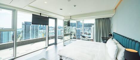 Una habitación de hotel moderna con una cama grande, vistas a la ciudad y un balcón.