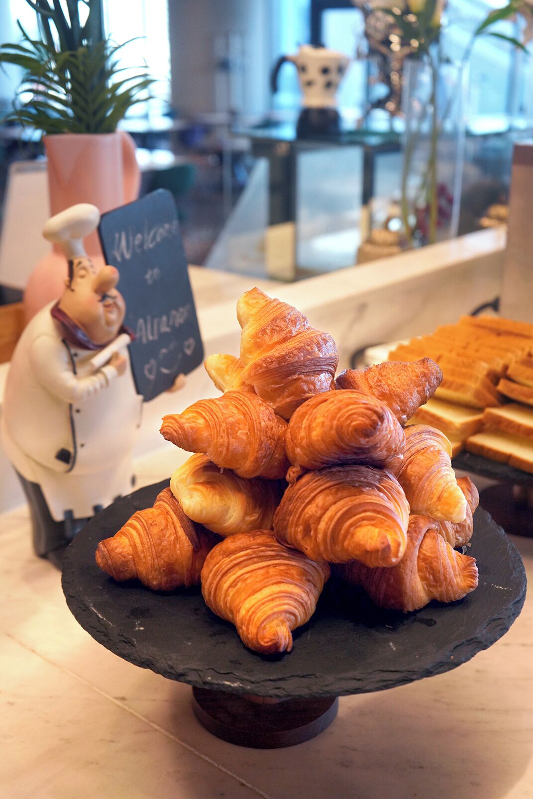 A stack of croissants on a slate serving tray.