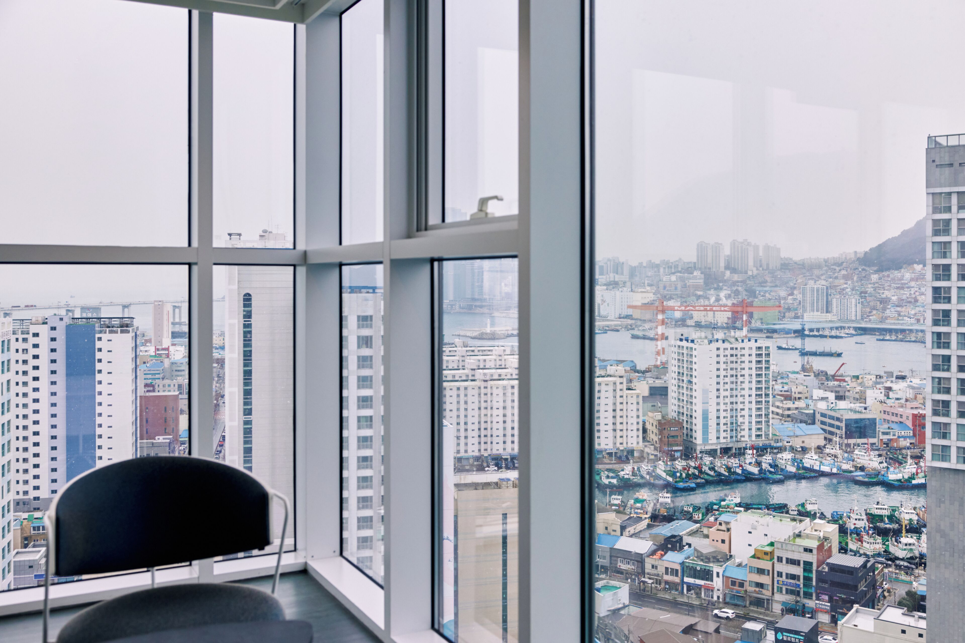 Quarto em um arranha-céu com uma grande janela com vista para a cidade e o porto.