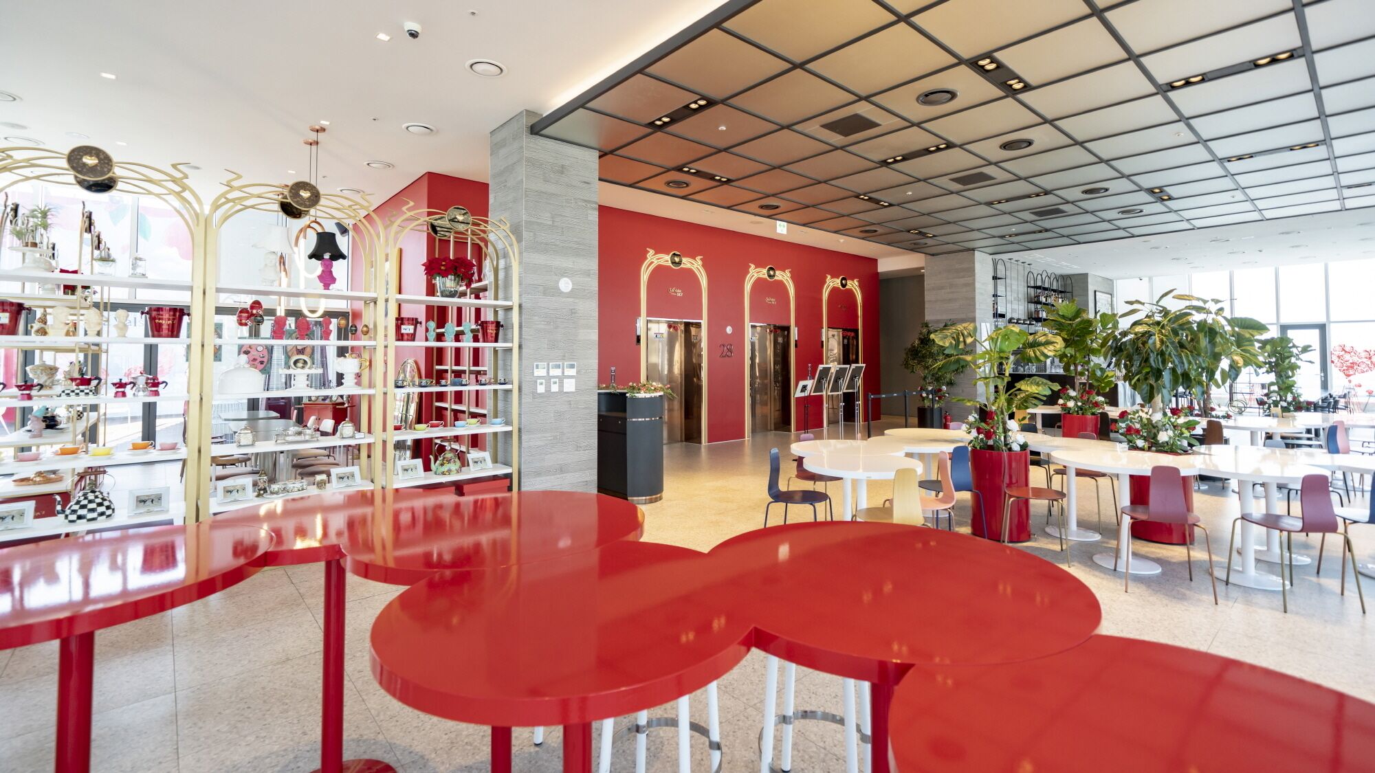 A modern interior with red and white decor, a central seating area, and a variety of displayed items on shelves.