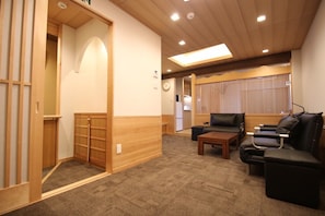 Experience a serene retreat with a sliding door, carpeted floor, and comfortable black leather sofa.
