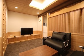 Relax in this stylish living room with a flat-screen TV, comfortable sofa, and wooden table.