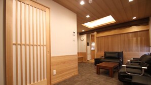 A room with a tatami mat floor, a sliding door, a sofa, a coffee table, and a ceiling light. - Kyoto Guest House Gion (Kyoto)