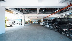 A parking garage with multiple vehicles, including cars and a motorcycle. - Travelbee Fuente Inn (Cebu City)