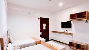 A modern hotel room with two single beds, a desk, a chair, a TV, and built-in wooden shelves. - Travelbee Fuente Inn (Cebu City)