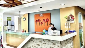 A reception area with a modern design, featuring a wooden ceiling, a glass counter, and a brick-patterned wall. - Travelbee Fuente Inn (Cebu City)