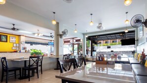 Un restaurant amb zona de bar, seients i vista al pati exterior.