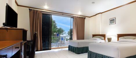 A hotel room with two beds, a TV, a desk, and a balcony with a view.