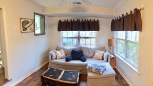 A cozy room with a curved window, a sofa, a small table, and a lamp. - Cozy cottage on the lake (Liberty Hill)