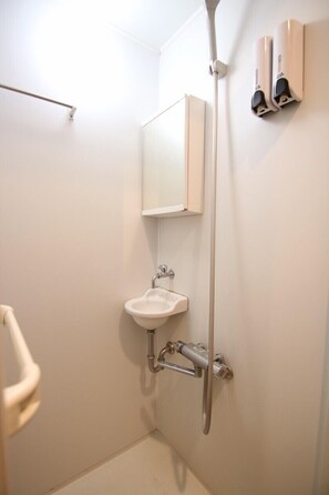 A small, white bathroom with a sink, mirror, and two soap dispensers on the wall. - Private Residence Kyoto Kiyomizu (Kyoto)