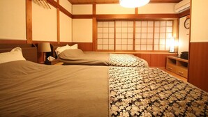A traditional Japanese-style room with two beds, wooden beams, a shoji screen, and a ceiling fan. - Private Residence Kyoto Kiyomizu (Kyoto)