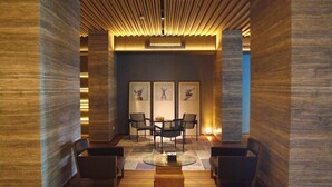 A modern lobby with a central seating area, framed artwork on the back wall, and wooden paneling on the walls. - PULANG ke UTTARA (Depok)
