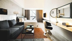 A modern hotel room with a bed, a sofa, a desk, and a large mirror. - PULANG ke UTTARA (Depok)