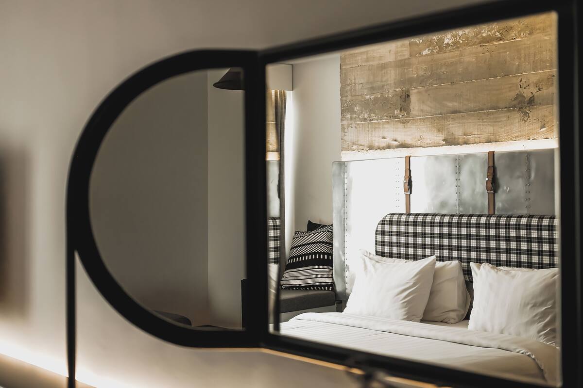 A bedroom with a bed, a headboard, and a mirror.