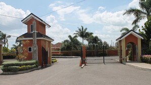 A gated entrance to a property with a red building, a small tower-like structure, and a gate. - Crimson Heights is a three bedroom house, in a Secured Gated Community (St Ann’s Bay)