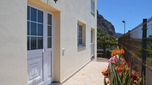 Un edificio con puertas y ventanas blancas, un camino de baldosas y una valla metálica adornada con flores.