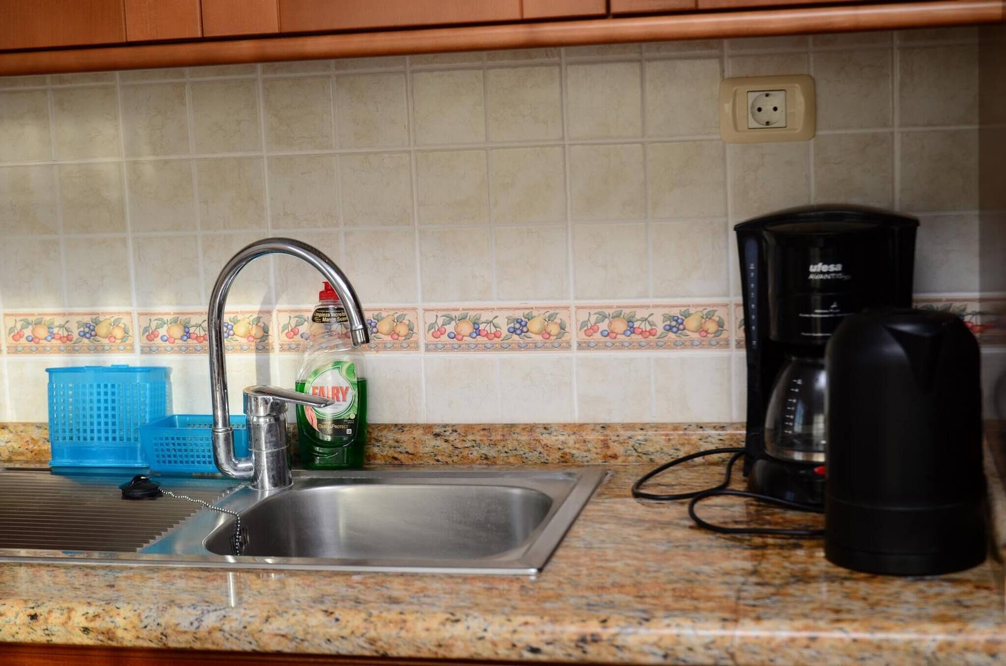 Eine Küche mit Spüle aus Edelstahl, einer Kaffeemaschine und einem Wasserkocher.