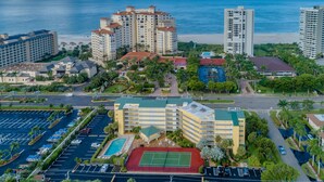 A high-rise hotel complex with multiple buildings, a swimming pool, tennis courts, and a parking area. - 5th Fl condo, steps to JW Marriott & Beach, Sunset Views, walk to restaurants (Marco Island)