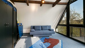 A room with a blue sofa, a wooden ceiling, and a large window. - RügenHeart 3 Dachträume - RügenHeart 3 Dachträume (Parchtitz)