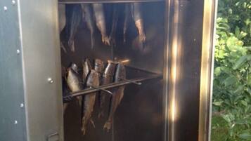 Ein Outdoor-Grill aus Metall mit Fisch, der in Aufhängenetzen darin hängt.