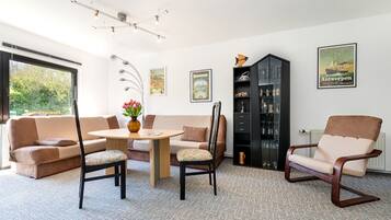 A modern living room with a sofa, two armchairs, a coffee table, and a cabinet.