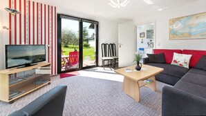 A modern living room with a TV, sofa, coffee table, and a sliding glass door leading to a patio.