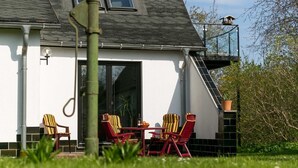 A house with a balcony, a dining area with chairs, and a window.