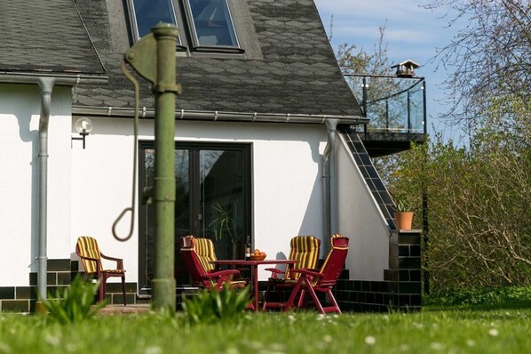 A house with a balcony, a dining area with chairs, and a window.