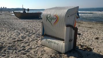 En strandstol med et logo, en båd i baggrunden og en sandstrand.