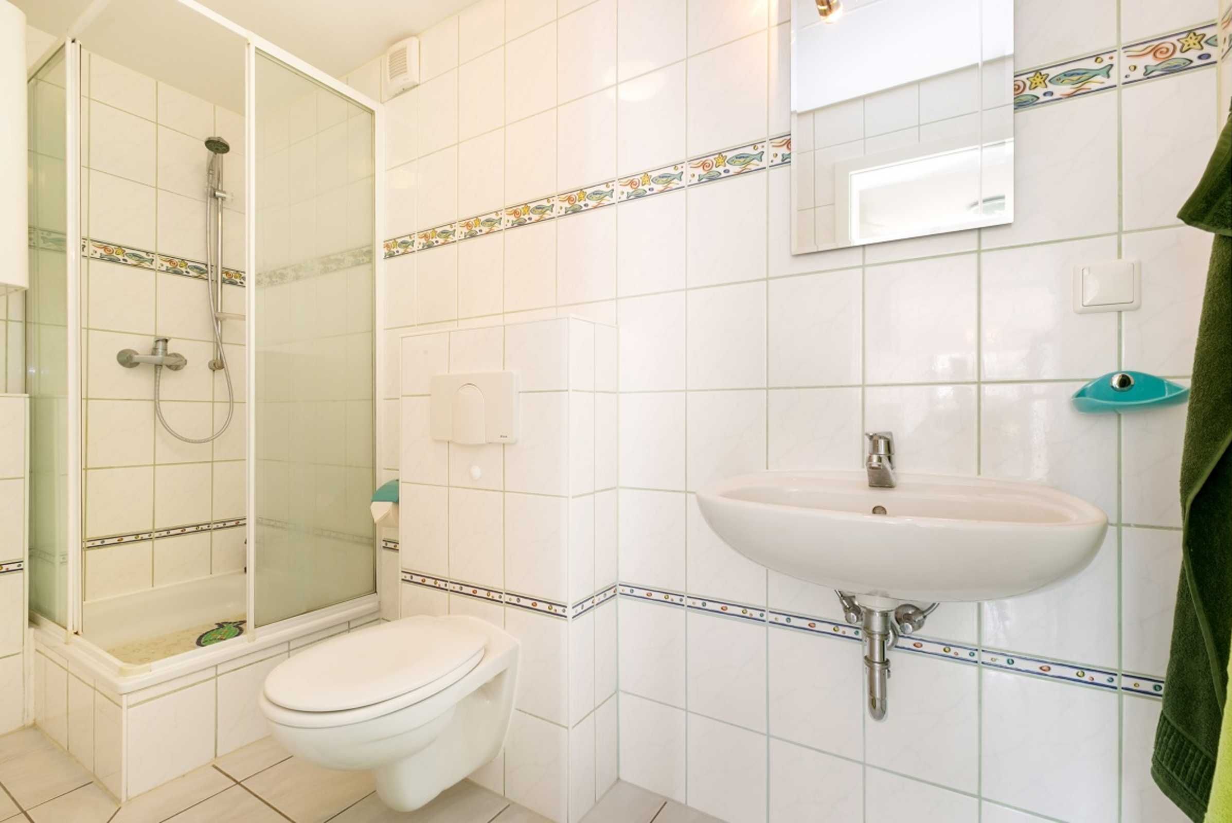 A bathroom with a shower, toilet, sink, and a mirror.