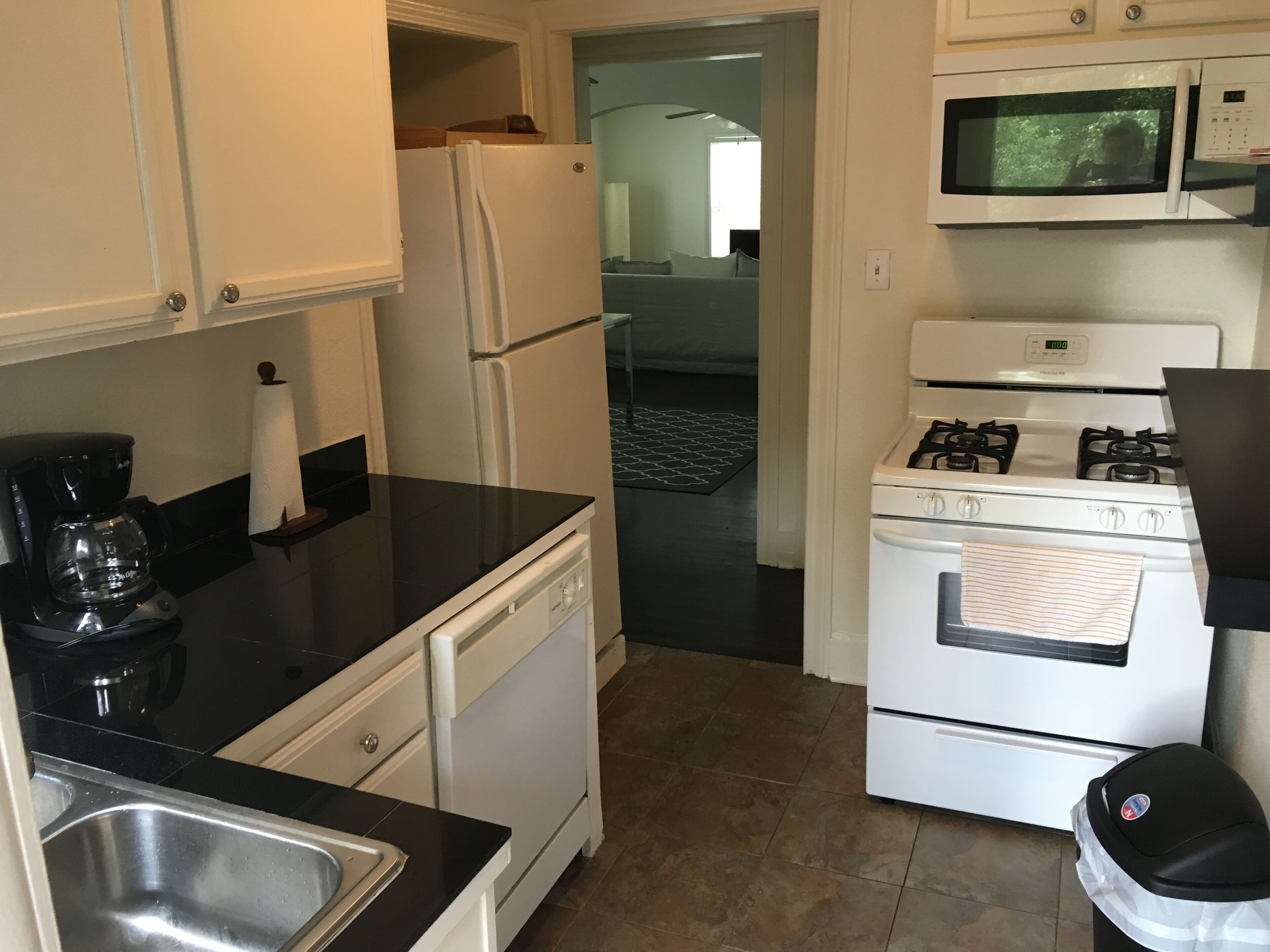 A compact kitchen with a refrigerator, microwave, stove, and sink.