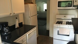 Eine kleine Küche mit Kühlschrank, Mikrowelle, Herd und Spüle.