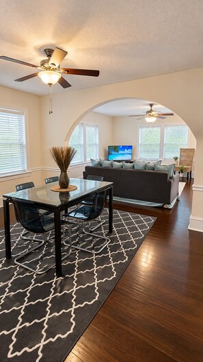 A living room with a sofa, TV, and ceiling fans.