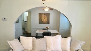 Ein Wohnzimmer mit einer Couch, einem Esstisch und einem Gemälde an der Wand.